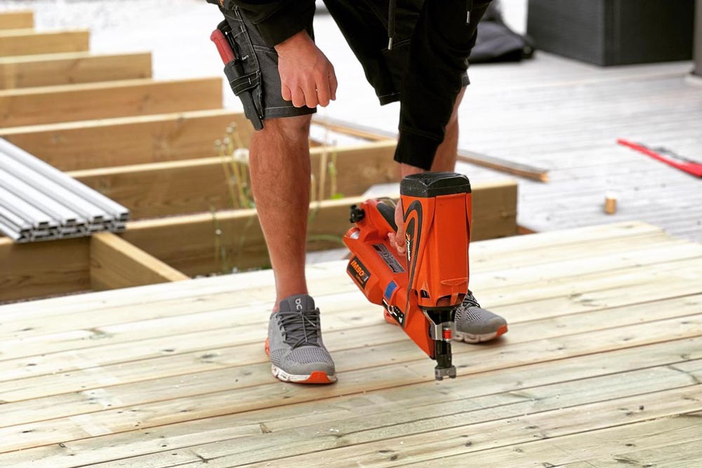 Medarbetare som spikar plankor på en altan